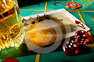 Gaming table in casino with glass of whiskey and set of four aces. Close up of a dark gambling poker table with booze