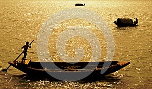 Ganges Delta, Bangladesh: A boat being paddled on the river and silhouetted against the sun photo