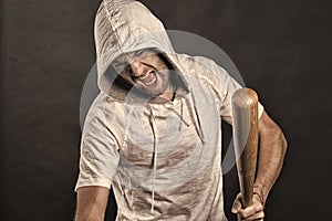 Gangster shout with bat weapon. Bearded man hold baseball bat. Angry hooligan wear hood in hoodie tshirt. Aggression or