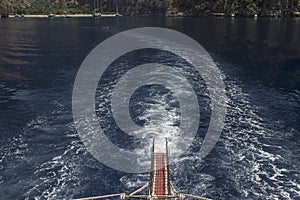 Gangway and trail at sea from a yacht, blue sea, away - rocks