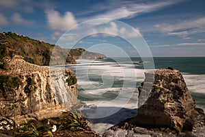 Gannett colony on the rocks above Muriwai Beach on the West coast of New Zealand, long exposure to smooth out the water and give