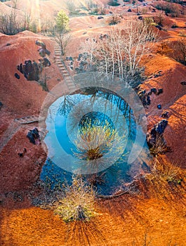 Gant, Hungary - Aerial view of abandoned bauxite mine with small blue lake and warm red and orange colors