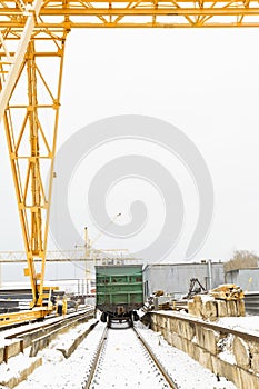 Gantry crane over railway carriage in outdoor warehouse