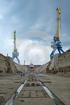 The gantry crane working at the seaport against the clouds