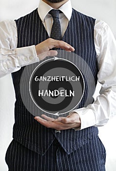 Ganzheitlich handeln - act holistically - text on a circle in the middle of the hands of a man