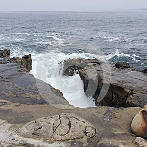 A gap in a rock wall looking out at the ocean and waves photo