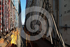 Gap between rows of different colors containers stacked on each other and secured on the container ship and lashed.