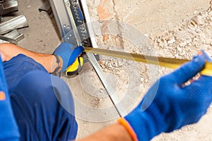 Garage Door Installation. Worker use a ruler to verify correct installation of metal profile.