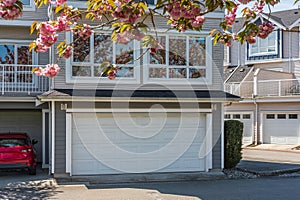Garage door with short driveway. Nice neighborhood on a sunny day. Row of garage doors at parking area for townhouses