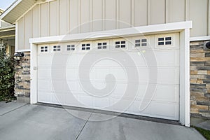Garage exterior with concrete driveway and white sectional door with window panels