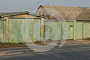 garage with green gates and part of the fence on the street