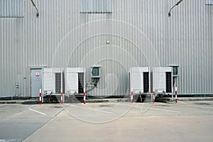 A garage of a large industrial building with both big air with a traffic cone warning condition beside a corrugated metal fence