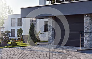 Garage of a modern European house with an automatic door next to garden plants