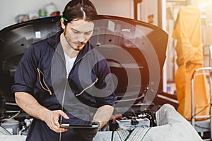 Garage technician worker using tablet computer advance technology for service checking and tuning car ECU at automobile car photo