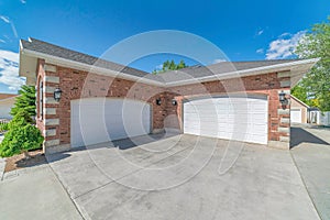 Garage with two arched white doors and red brick wall against sunny blue sky