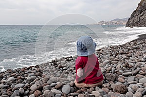 Garajau - Small toddler playing on idyllic volcanic black stone beach of Praia Garajai, Canico, Madeira island, Portugal