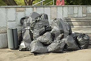 Garbage bags on the street. Black waste bags. Plastic bags with household waste collected in the park