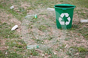 Garbage bin next to plastic trash on a ground background. Bright container for rubbish recycling. Environment, ecology