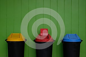 garbage bins with colourful lids for recycling and general household waste with green color wall background