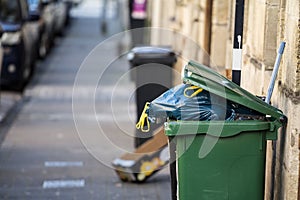 Garbage bins and containers full, overflowing, with bags falling on ground in residential area of Bordeaux, France photo
