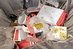 Garbage can with the remains of disposable food packaging and disposable glasses of soft drinks