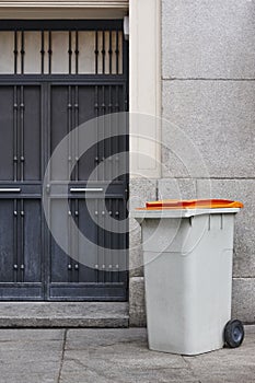 Garbage can on an urban building entrance door. Green environment