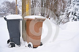 Garbage cans at the roadside on a snowed-in street in Germany