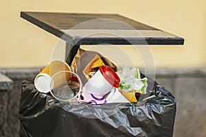 Garbage in a city street trash can closeup, plastic and paper takeaway cups. Disposal and Recycled processing concept