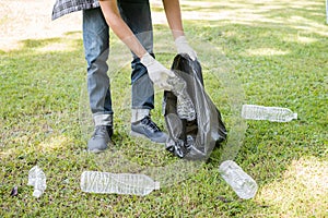 Garbage collection, Man`s hands pick up plastic bottles, put garbage in black garbage bags to clean up at parks, avoid pollution,