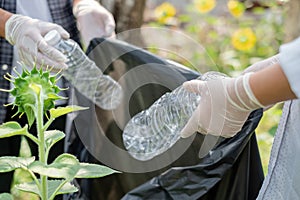 garbage collection, volunteer team picking up plastic bottles, putting garbage in black garbage bags to clean up at parks,