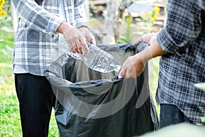 garbage collection, volunteer team picking up plastic bottles, putting garbage in black garbage bags to clean up at parks,