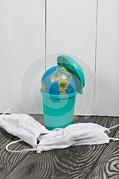 Garbage container with a globe. Nearby are protective masks during the pandemic