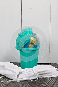 Garbage container with a globe. Nearby are protective masks during the pandemic