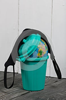 Garbage container with a globe. He is wearing a protective mask during a pandemic