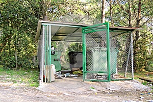 Garbage containers in fence cage / Orderly stowed garbage cans for separate garbage collection.