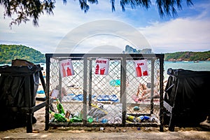 Garbage containers for separate waste collection on the tropical beach near people who sunbathing
