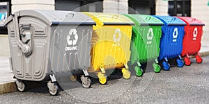 Garbage containers with separated garbage on a street. Trash bins for plastic, glass, paper and organic. Segregate waste and