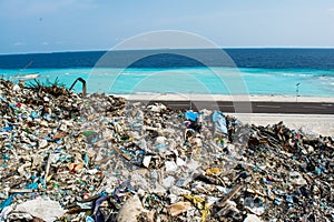 Garbage dump near the beach close to ocean full of smoke, litter, plastic bottles,rubbish and trash at tropical island