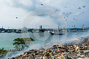 Garbage dump near harbor view full of smoke, litter, plastic bottles,rubbish and trash at the Thilafushi local tropical island