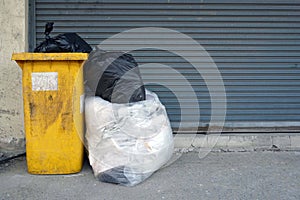 Garbage dumpster and trash can in the front steel fence of building