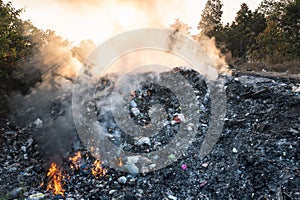 Garbage and fire burn in landfill cause of air pollution, environmental damage and global warming.