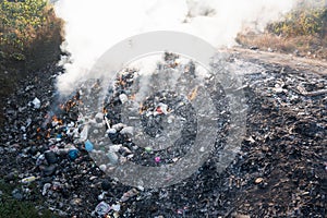 Garbage and fire burn in landfill cause of air pollution, environmental damage and global warming.