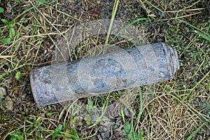 Garbage from a gray black charred metal cylinder lies on ground