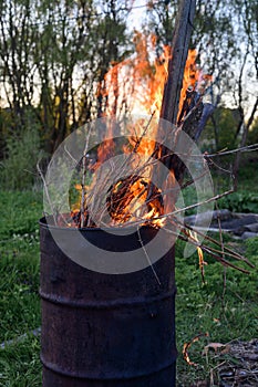 Garbage incineration in rusty metal barrel. burning branches and old grass from the land plot in a barrel. spring cleaning of the