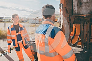 Garbage man and women cleaning dustbins into waste truck