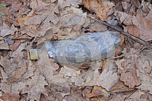 garbage from one old dirty white plastic bottle lies on the ground