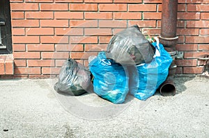 Garbage plastic bags full of junk dumped on the street waiting for dumpster truck to collect them