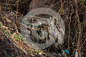 Garbage in the ravine. A pile of rubbish with a rubber tire in the forest. Pollution of nature