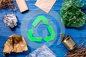 Garbage for recycling with recycling symbol on blue wooden background top view