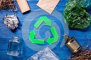 Garbage for recycling with recycling symbol on blue wooden background top view